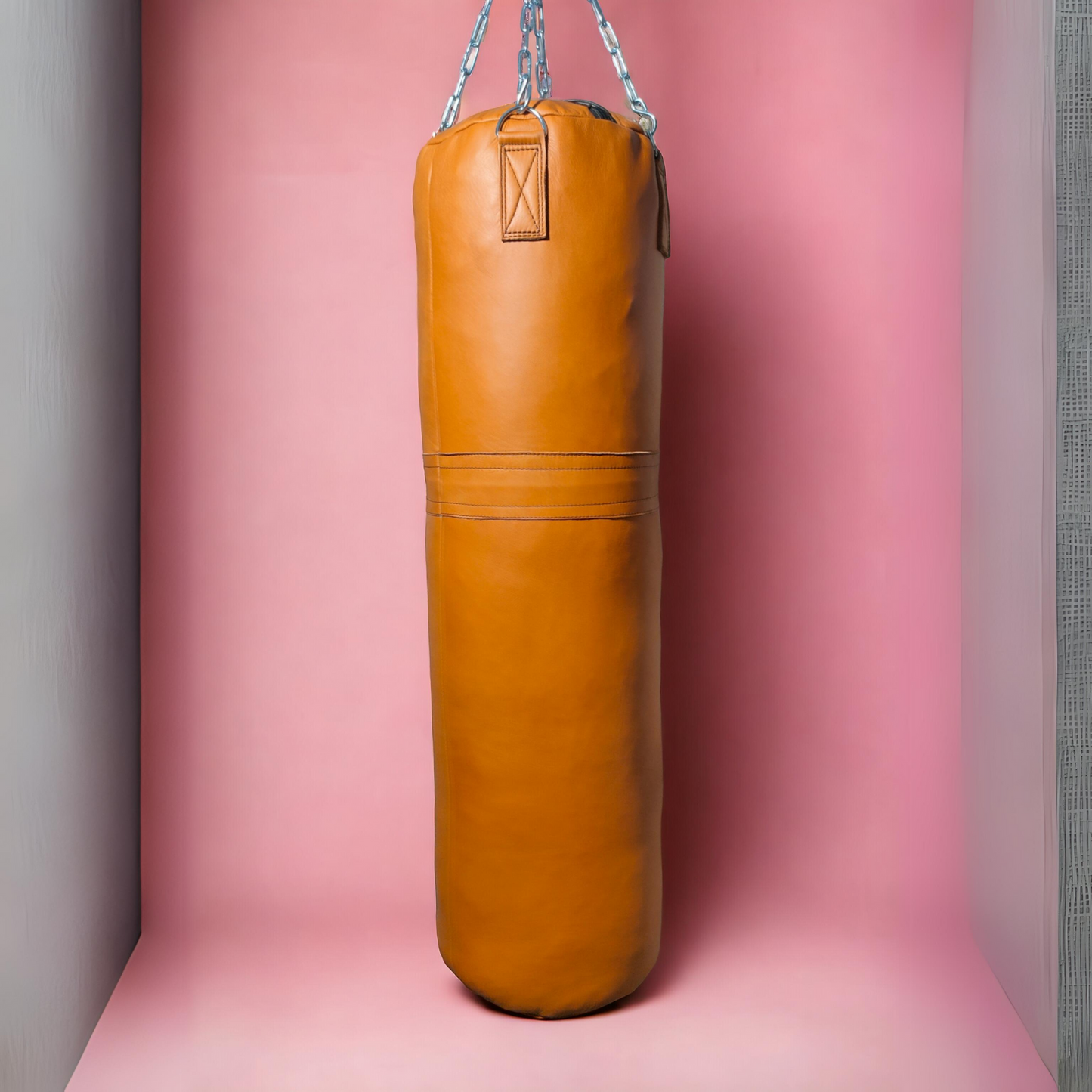 yellow leather punching bag hanging ith chains against the pink background