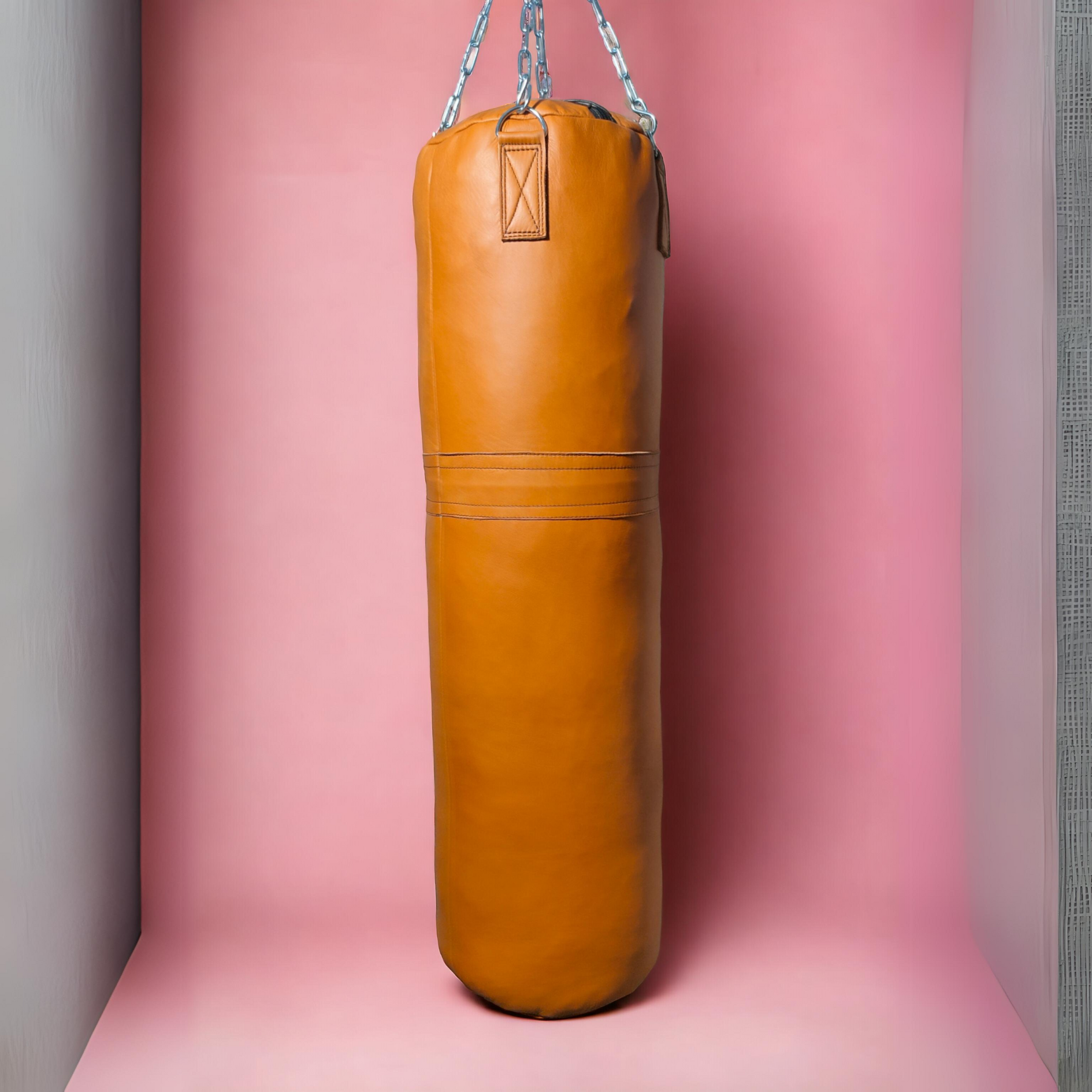 yellow leather punching bag hanging ith chains against the pink background