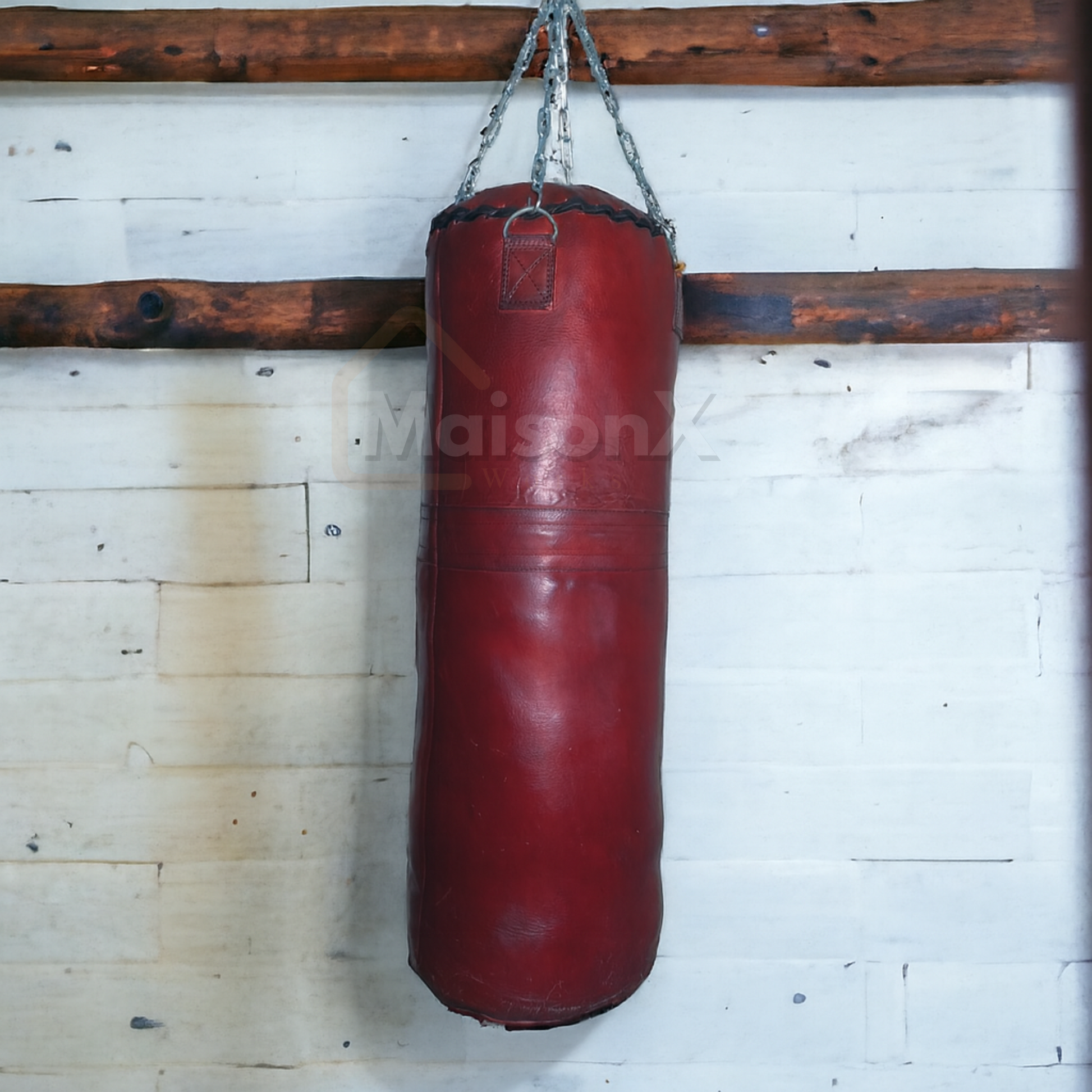 burgundy leather heavy bag for training hung against vintage wall with stainless steel chain of silver color. wall have 2  wood logs