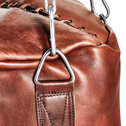 Close-up detail of the Blood-Fang Pro Punching Bag shows the durable heavy-duty cowhide texture and meticulous handmade heavy bag construction with reinforced stitching. This genuine leather heavy bag is essential Boxing Training Equipment and top-tier Gym Workout Gear. The vintage leather punching bag finish confirms the premium quality of the unfilled punching bag for serious MMA Kickboxing Bag sessions, secured by a professional steel chain
