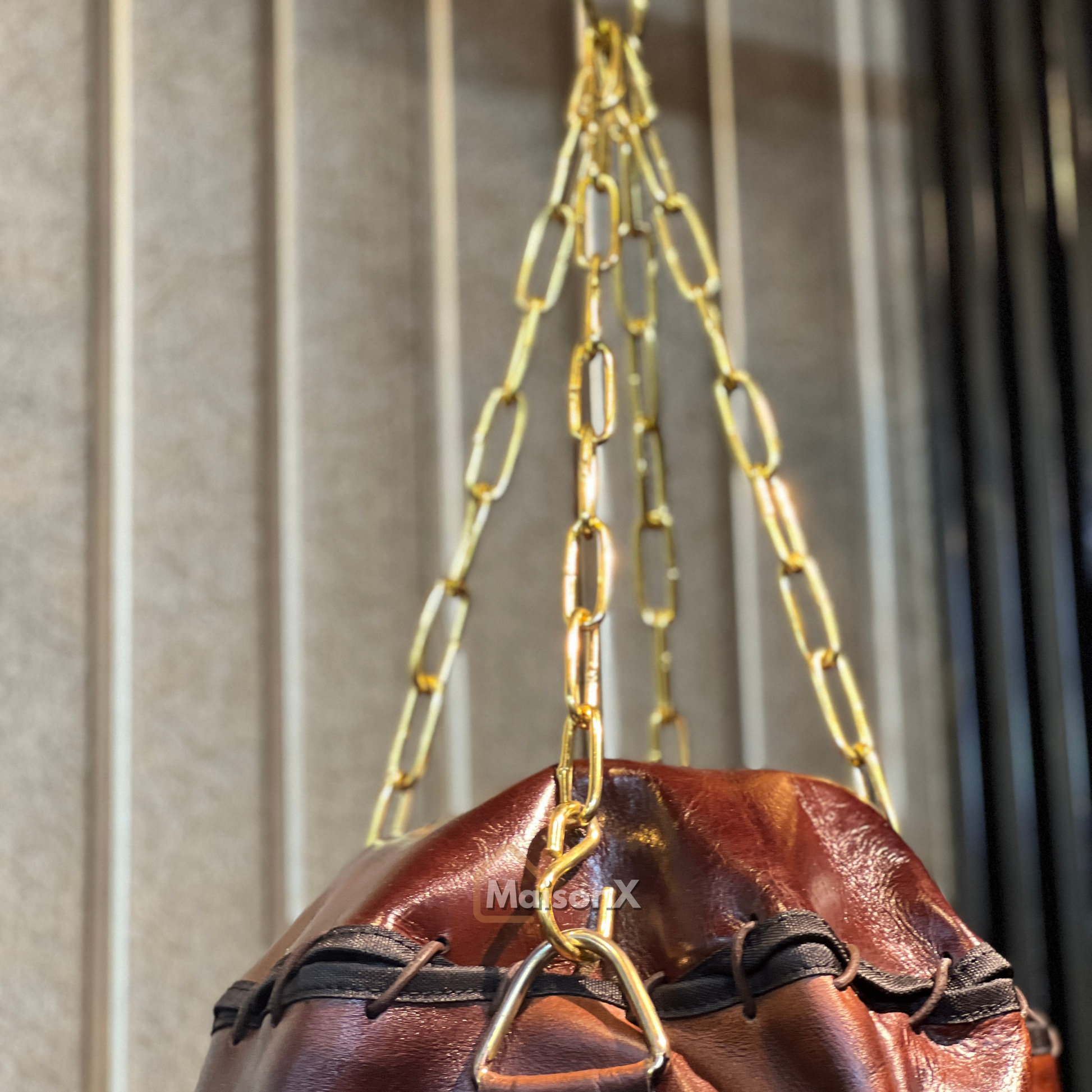 golden chain hanging the leather punching bag only showing the top half of punching bag, heavy bag is made of leather. high quality leather product with long life 