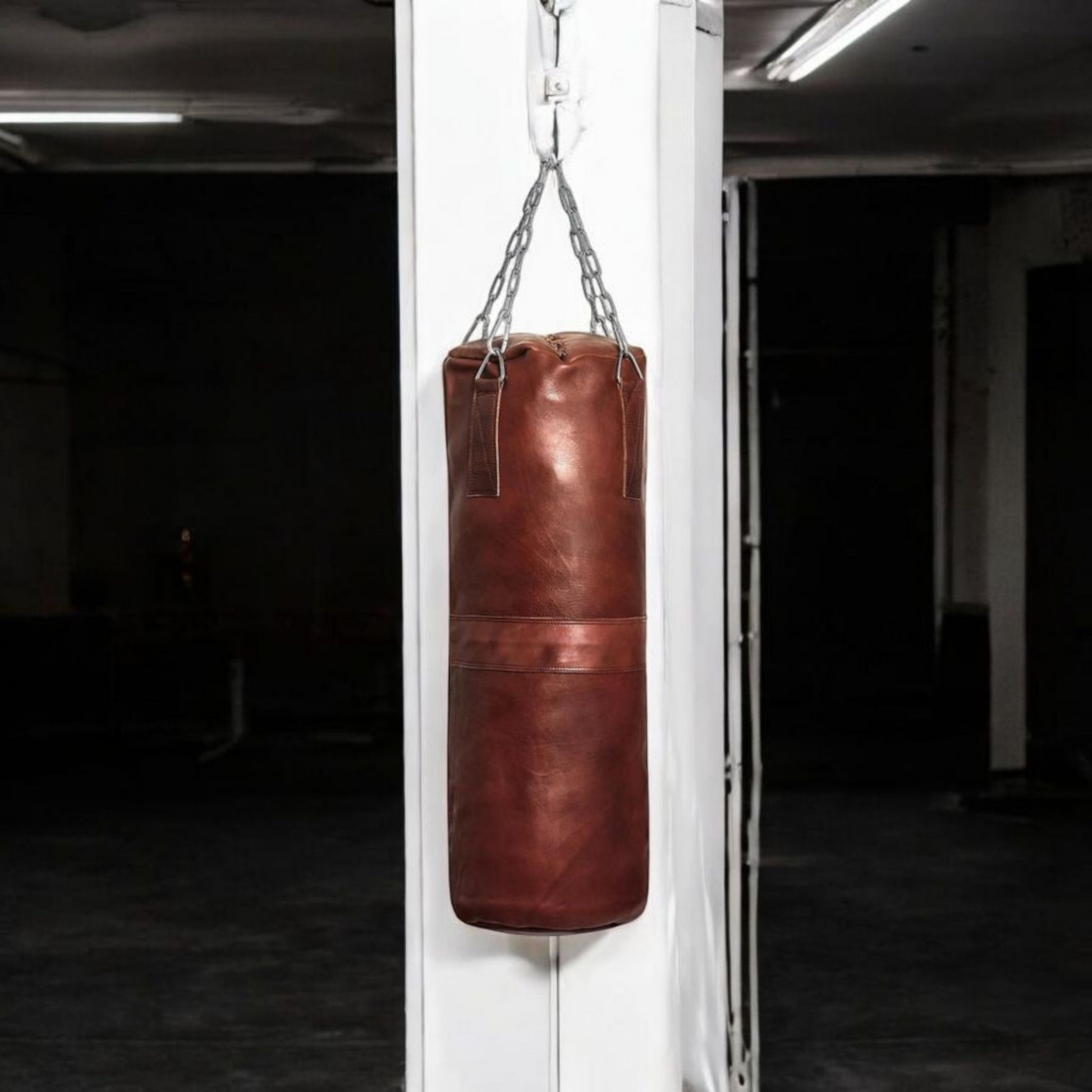 A large Blood-Fang Pro Punching Bag (up to 6 feet) hanging by its professional steel chain for a full-body MMA Kickboxing Bag or Boxing Training Equipment session. The heavy-duty cowhide genuine leather heavy bag is shipped as an unfilled punching bag, allowing customization. This handmade heavy bag is essential Gym Workout Gear and a classic vintage leather punching bag for any combat sport